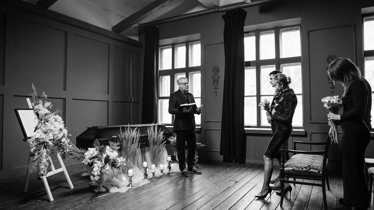 Intimate indoor funeral ceremony in grayscale, capturing solemn emotions.